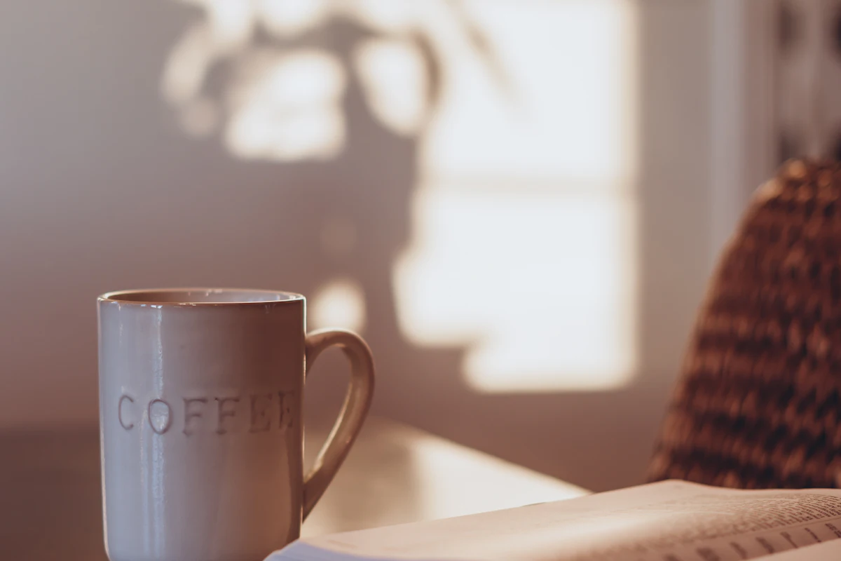 Une tasse à côté d’un livre ouvert sur une table